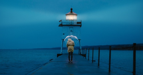 Person with Umbrella in Front of Lighthouse
